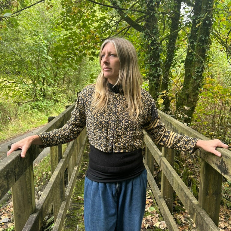 Woman wearing a black and ochre reclaimed cotton Gudri jacket with kantha stitching, front view.