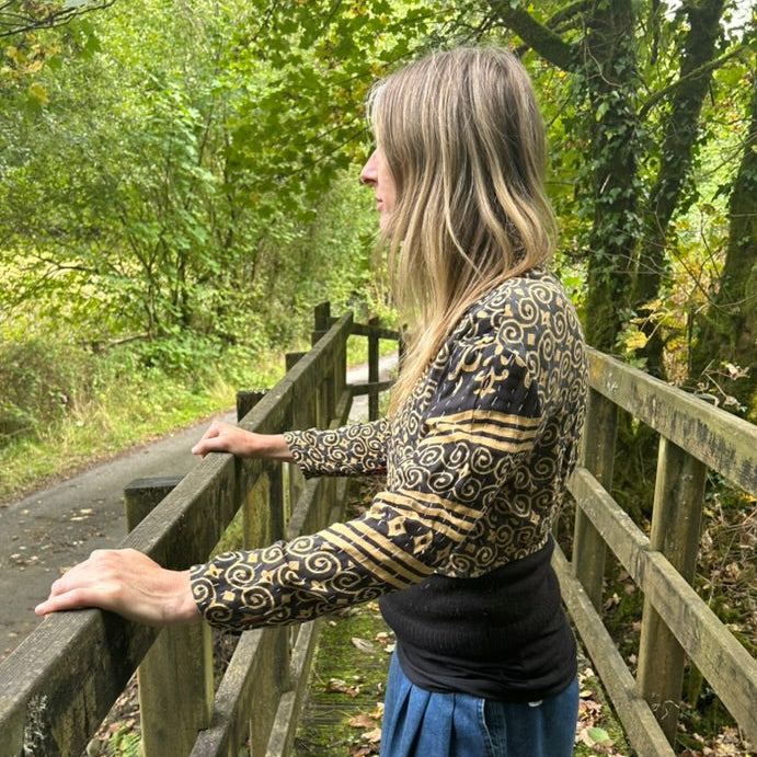Side view of black and ochre reclaimed cotton Gudri jacket with kantha stitching, showing the cropped fit and patterned sleeves.