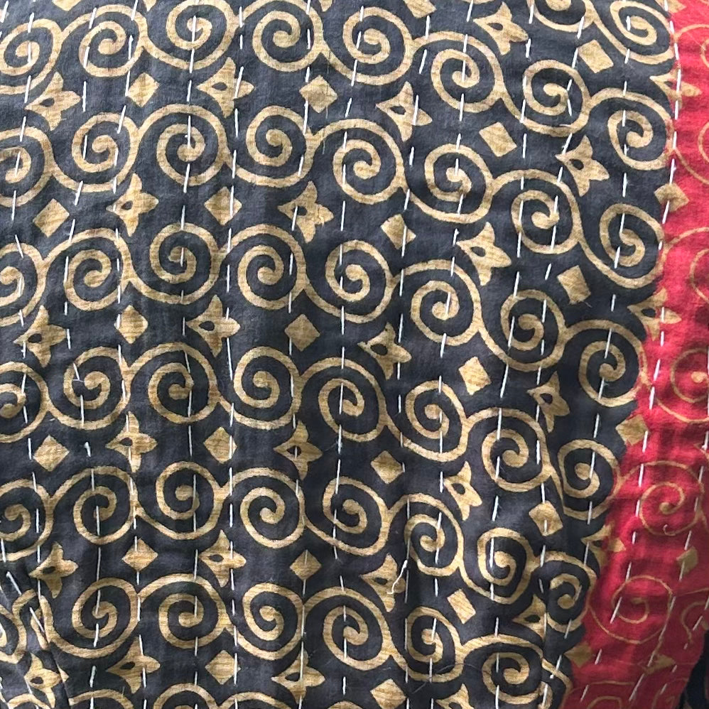 Close-up of black and ochre reclaimed cotton Gudri jacket showing traditional kantha running stitch and red contrast panel.